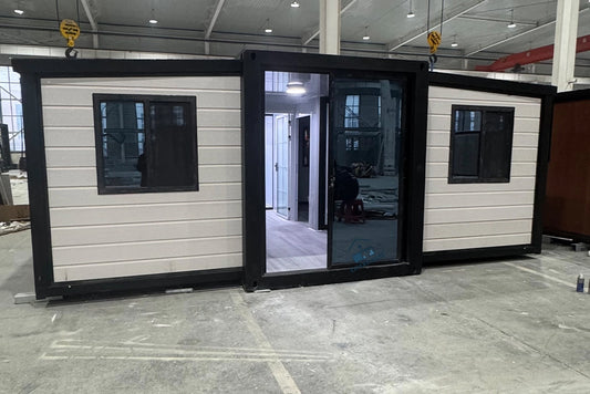 A 20ft expandable house with one bedroom, one bathroom, and one kitchen, featuring a white and black color scheme with large windows and a glass door.