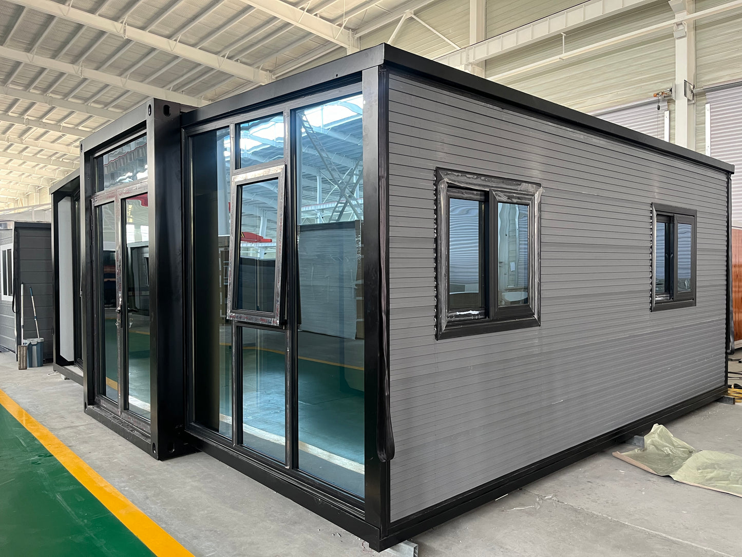 A modular housing unit with a gray exterior and large windows, designed to increase interior ceiling height.