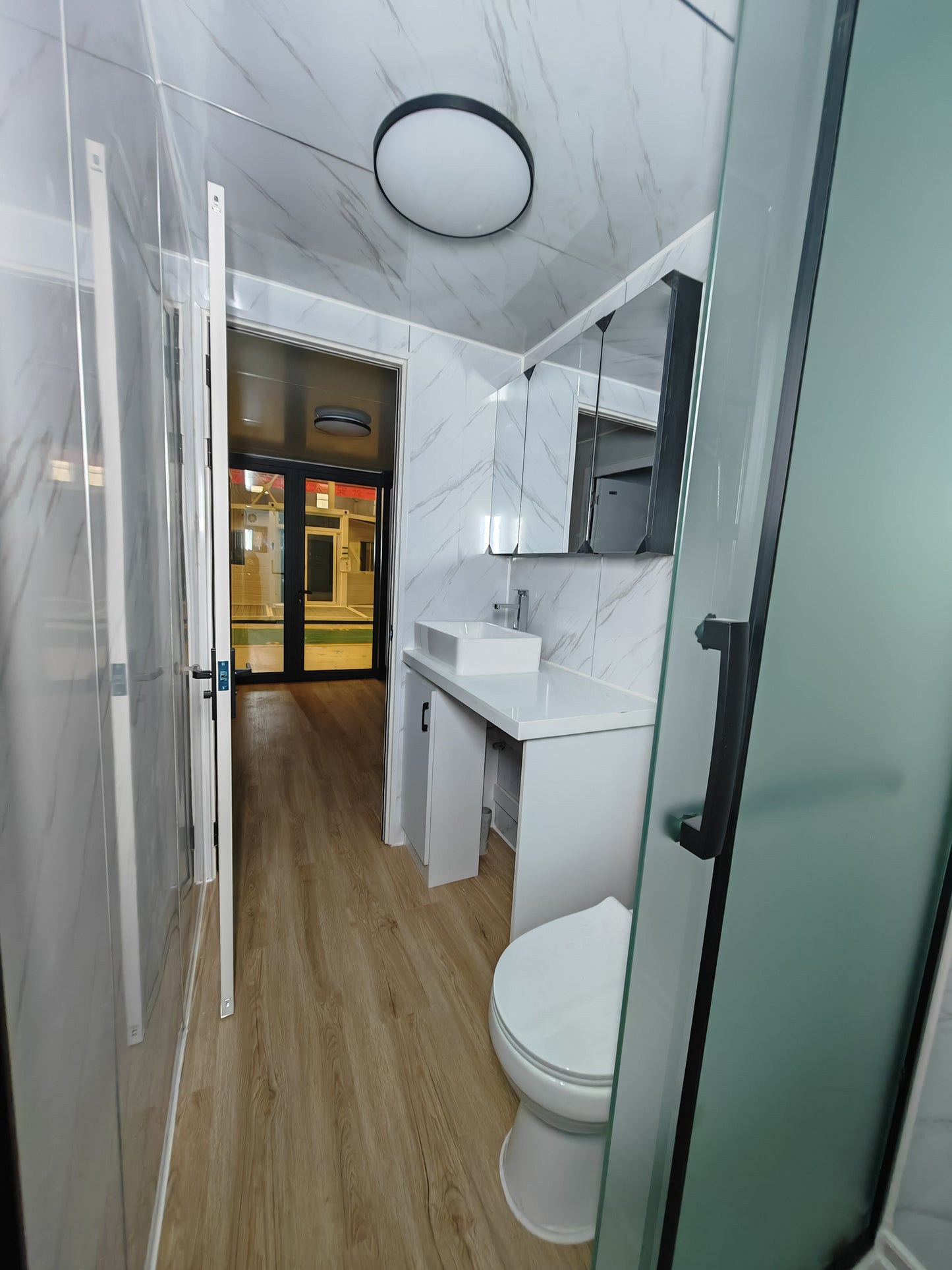 Modern bathroom with white tiles, a toilet, sink, and shower.