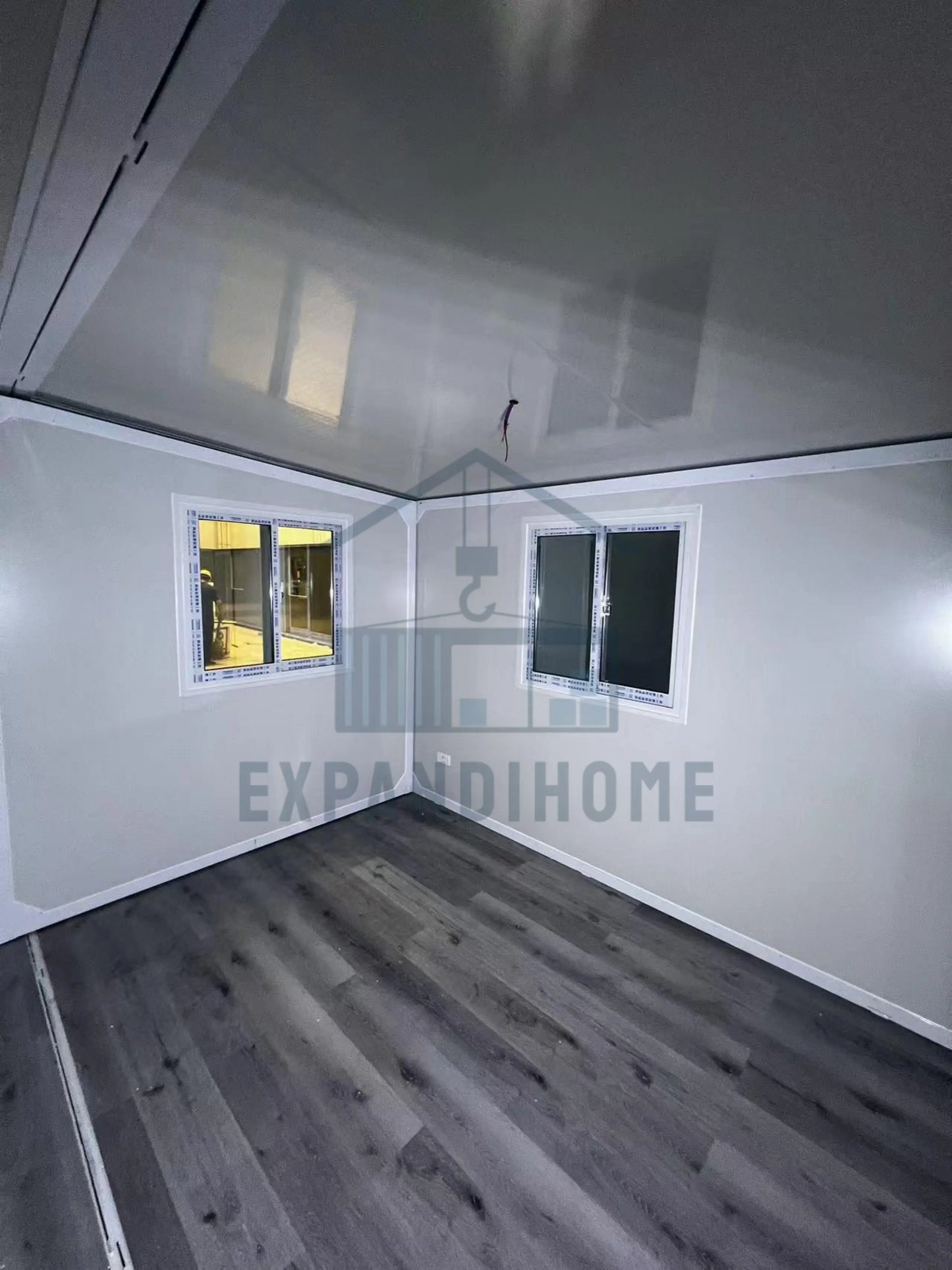 Small room with white walls, gray floor, and a small window. ExpandiHome logo visible.