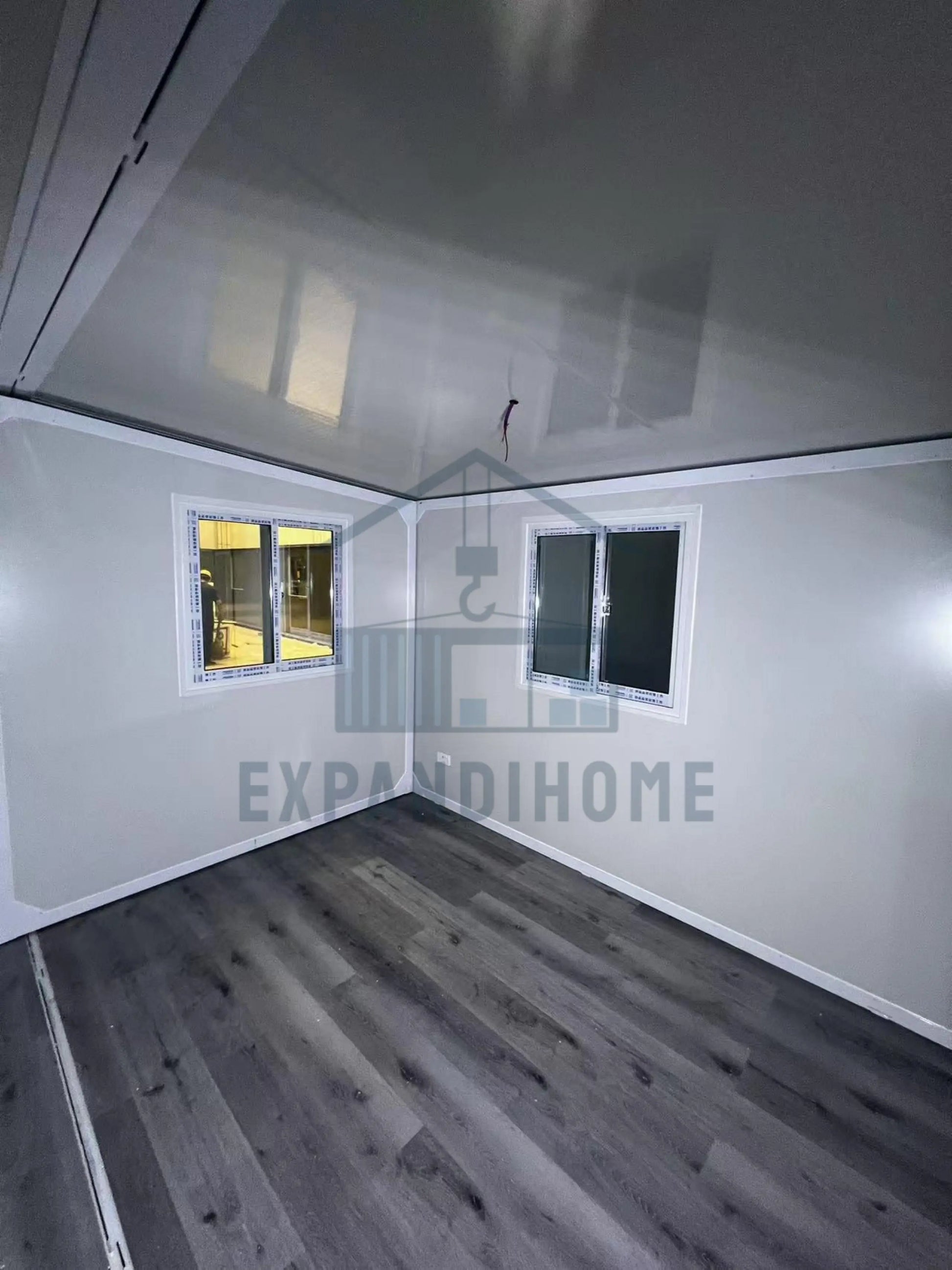 Small room with white walls, gray floor, and a small window. ExpandiHome logo visible.