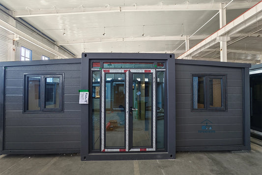 A 20ft expandable house with two bedrooms, one bathroom, and one kitchen, featuring a dark grey exterior, windows, and glass doors.
