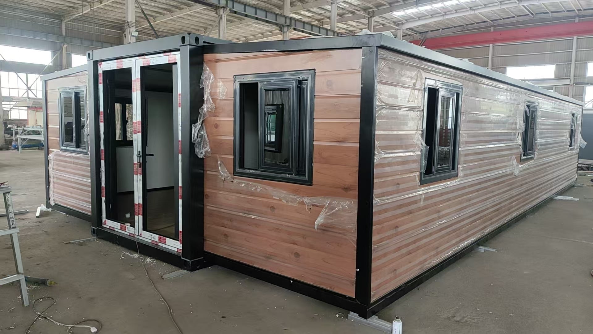 Modular building with wooden exterior and glass windows in a warehouse setting ExpandiHome