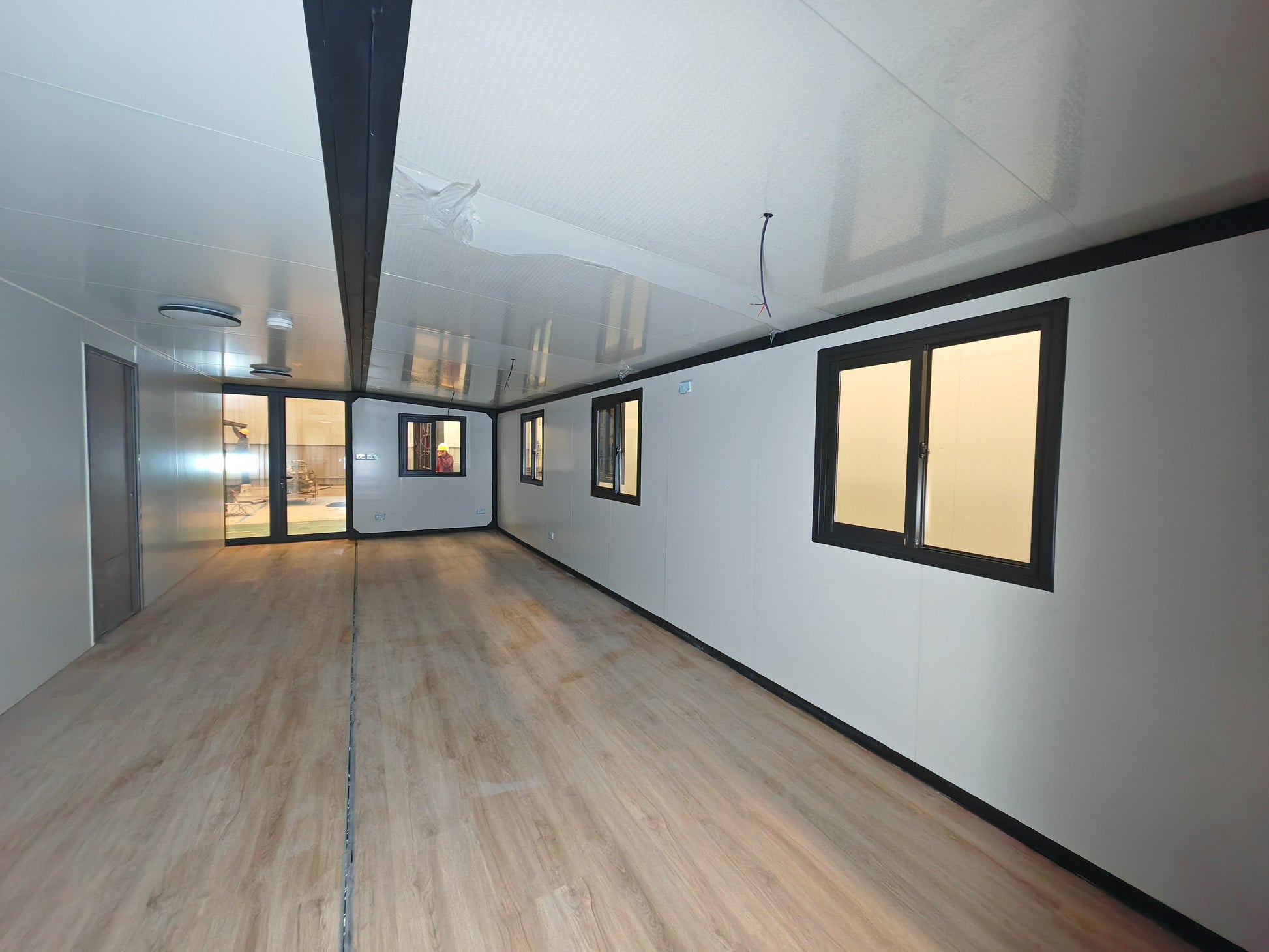 Modern room with white walls, wooden floor, and large windows.