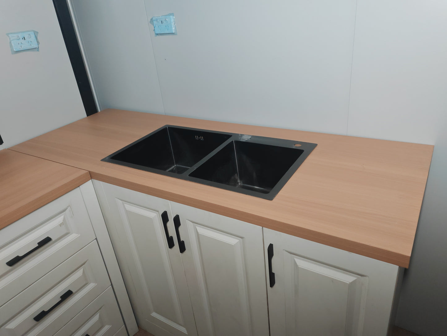Kitchen counter with a double sink and white cabinets.