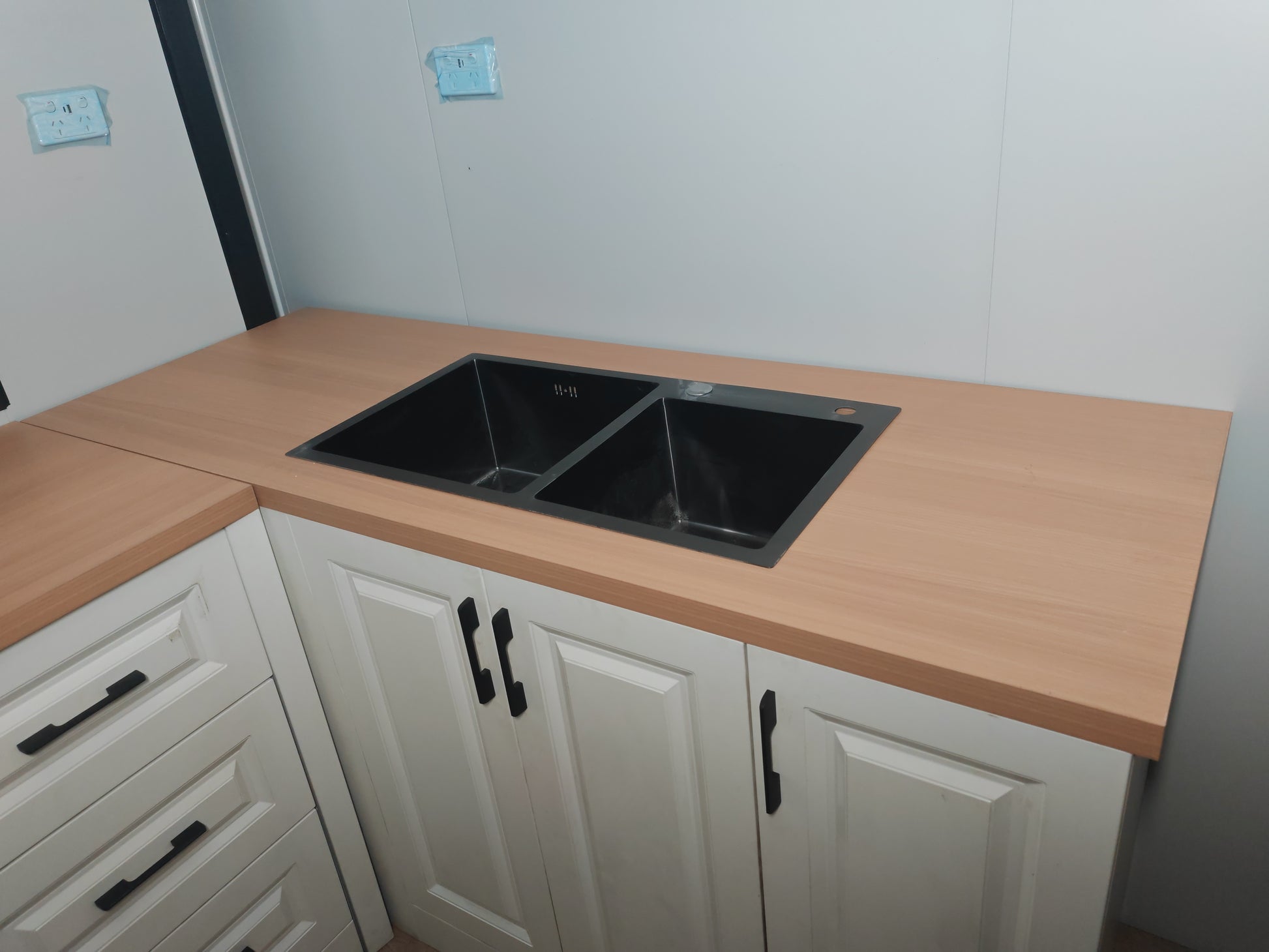 Kitchen counter with a double sink and white cabinets.