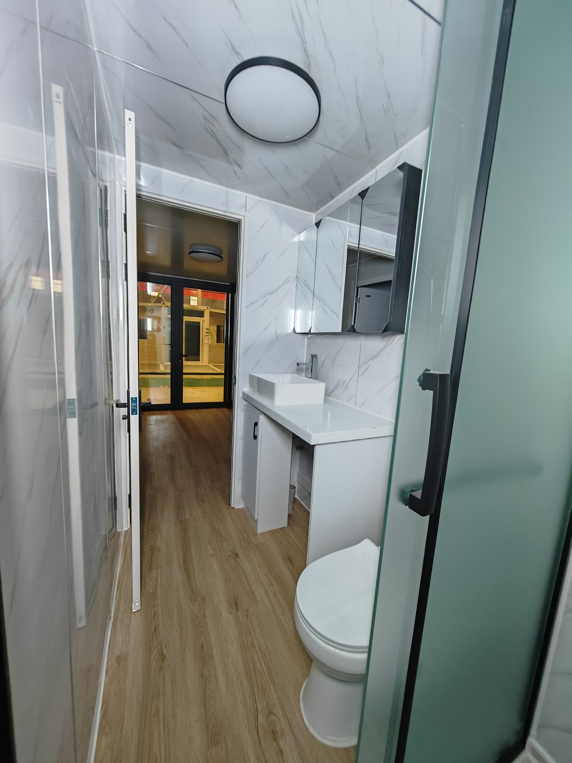 Modern bathroom with white tiles, a toilet, sink, and shower.