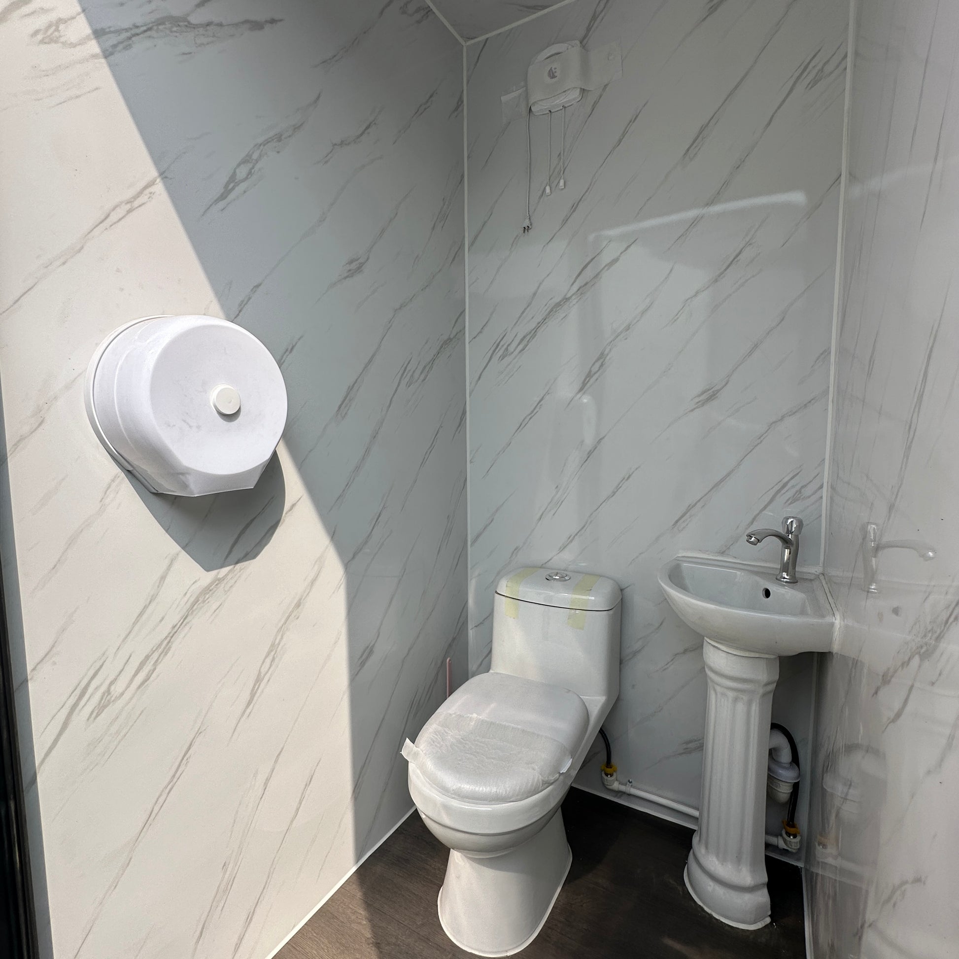 A portable toilet with a white marble-like interior, including a toilet, sink, and mirror.