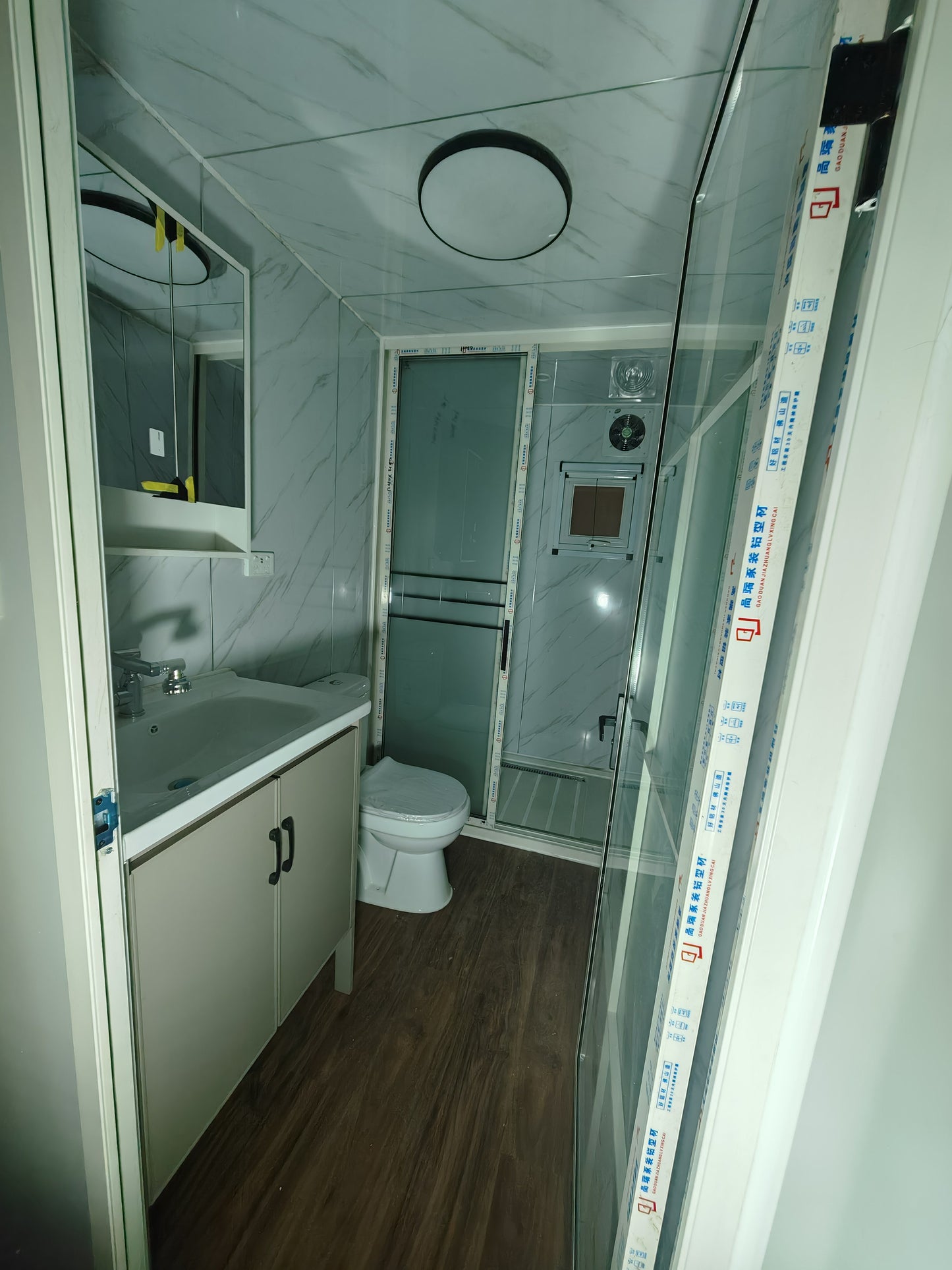 Compact bathroom with toilet, sink, and shower area.