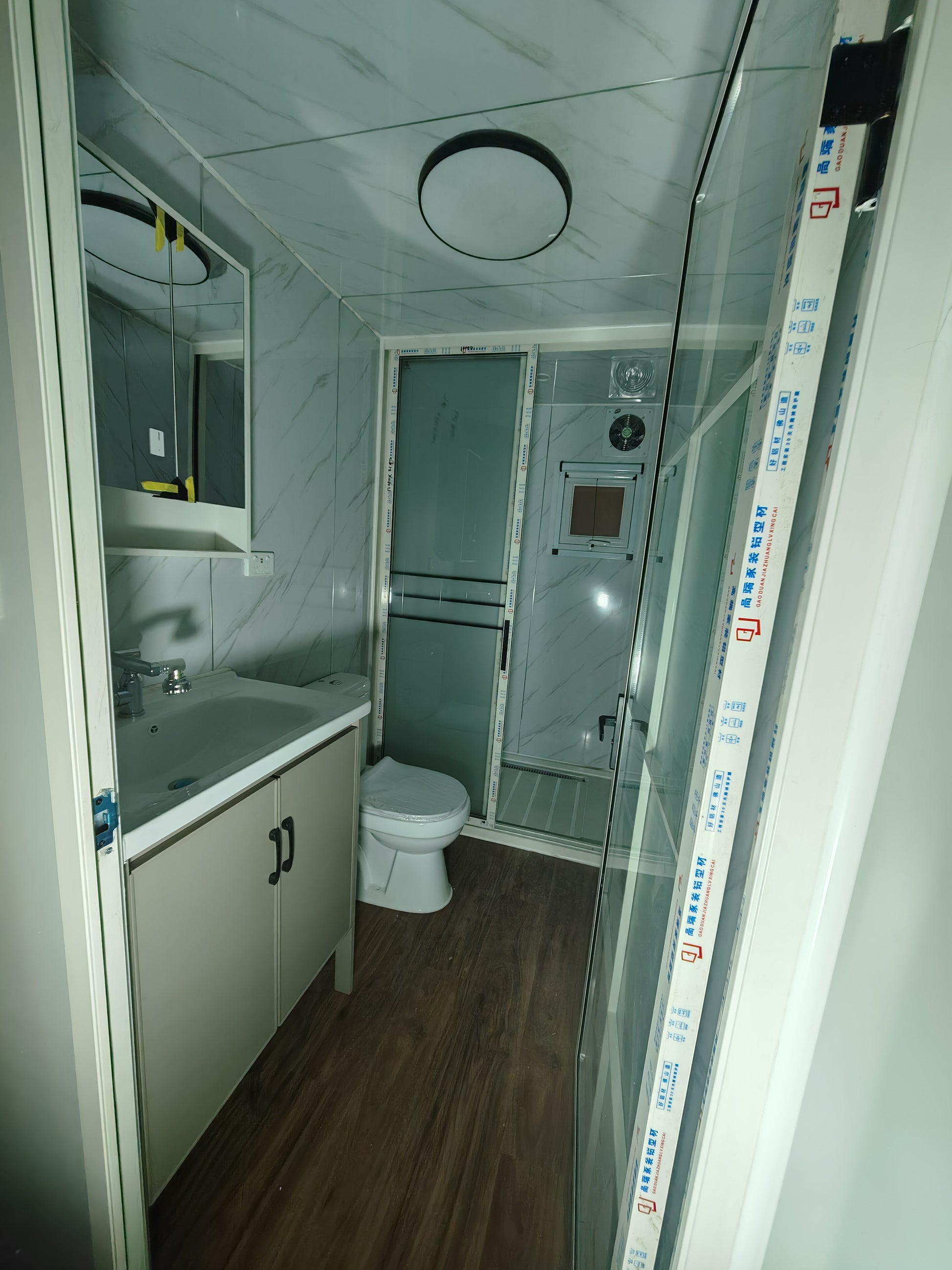 Compact bathroom with toilet, sink, and shower area.