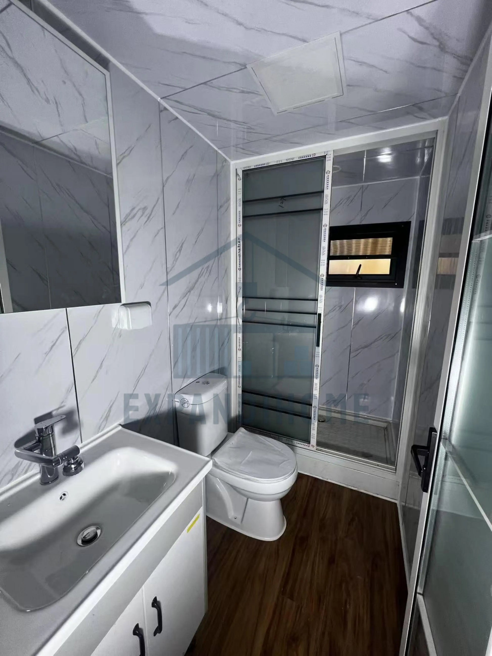 Modern bathroom with white tiles, sink, toilet, and shower.
