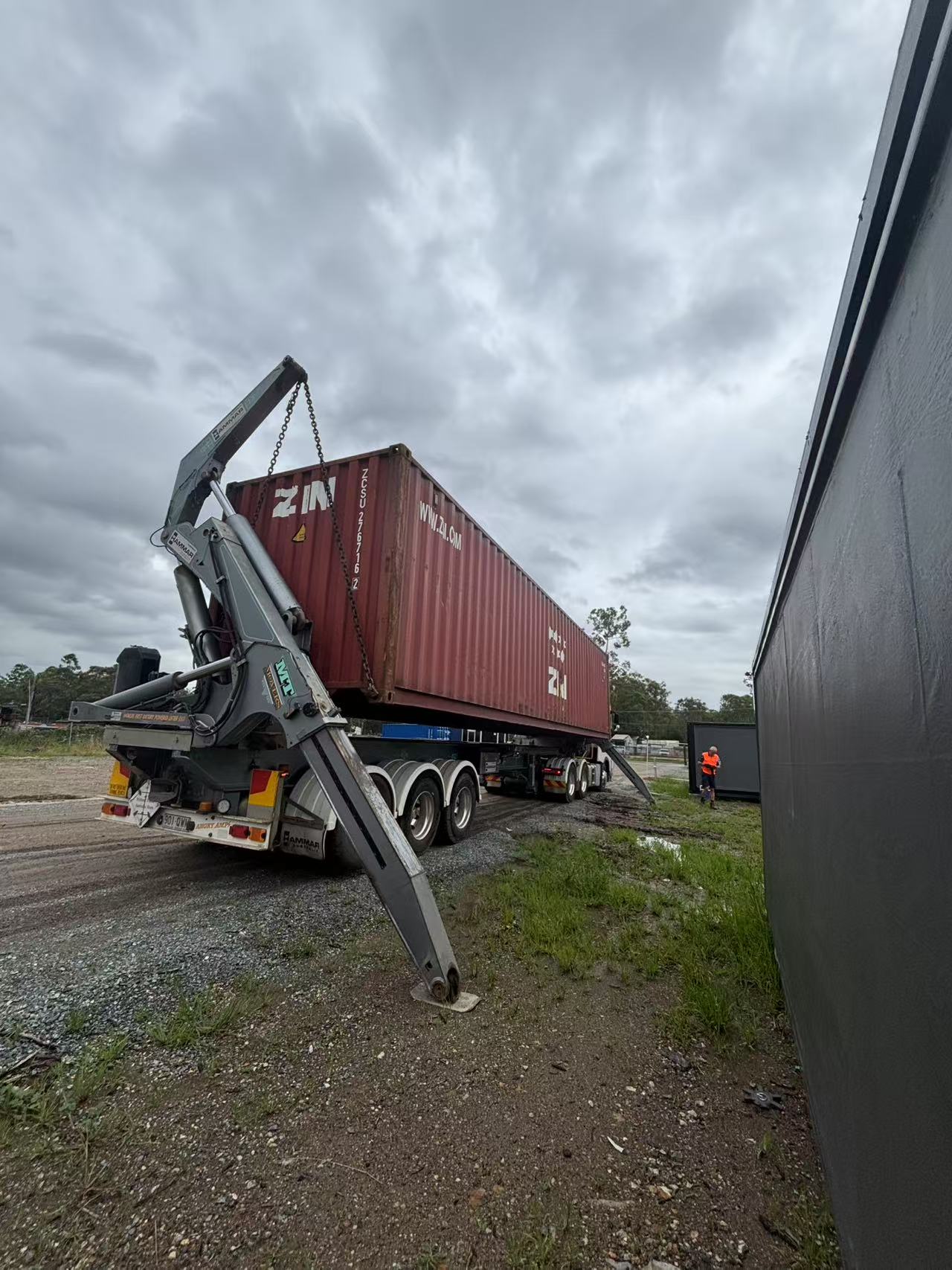 Container being lifted by a crane on a cloudy day