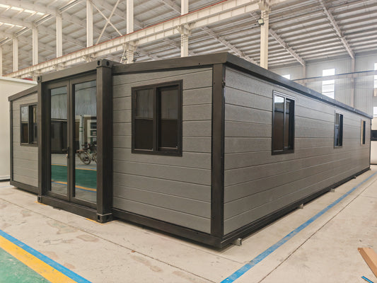 Modular building with gray exterior and black window frames in a warehouse setting.