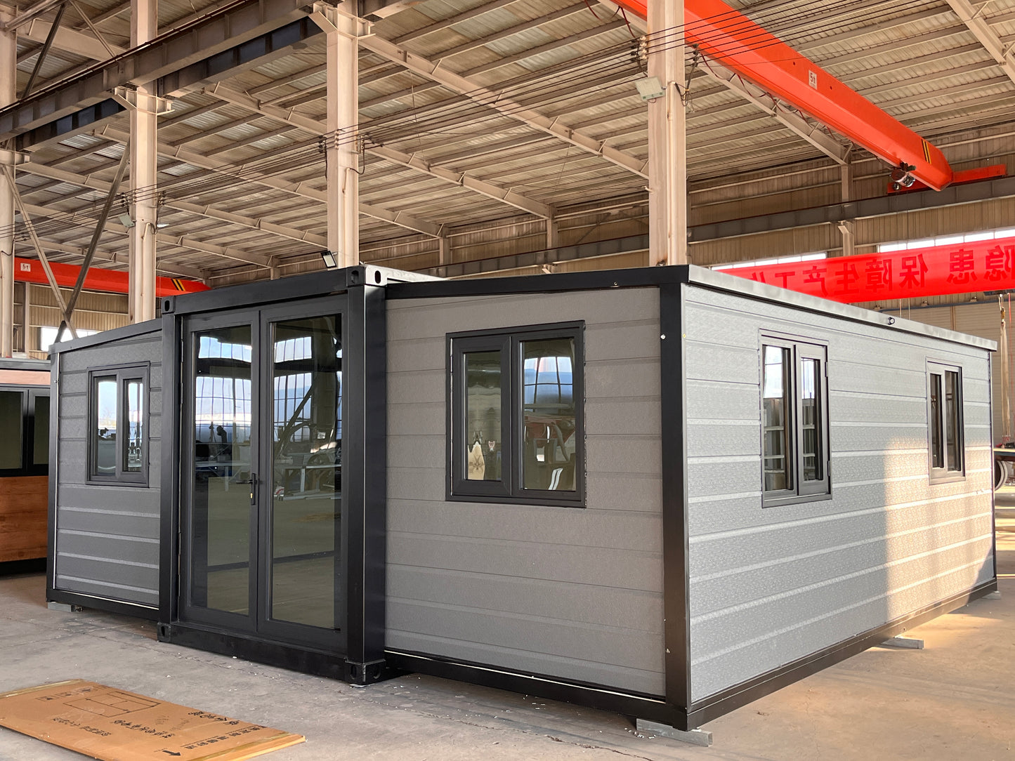 Modular building with gray exterior and black trim in a warehouse setting
