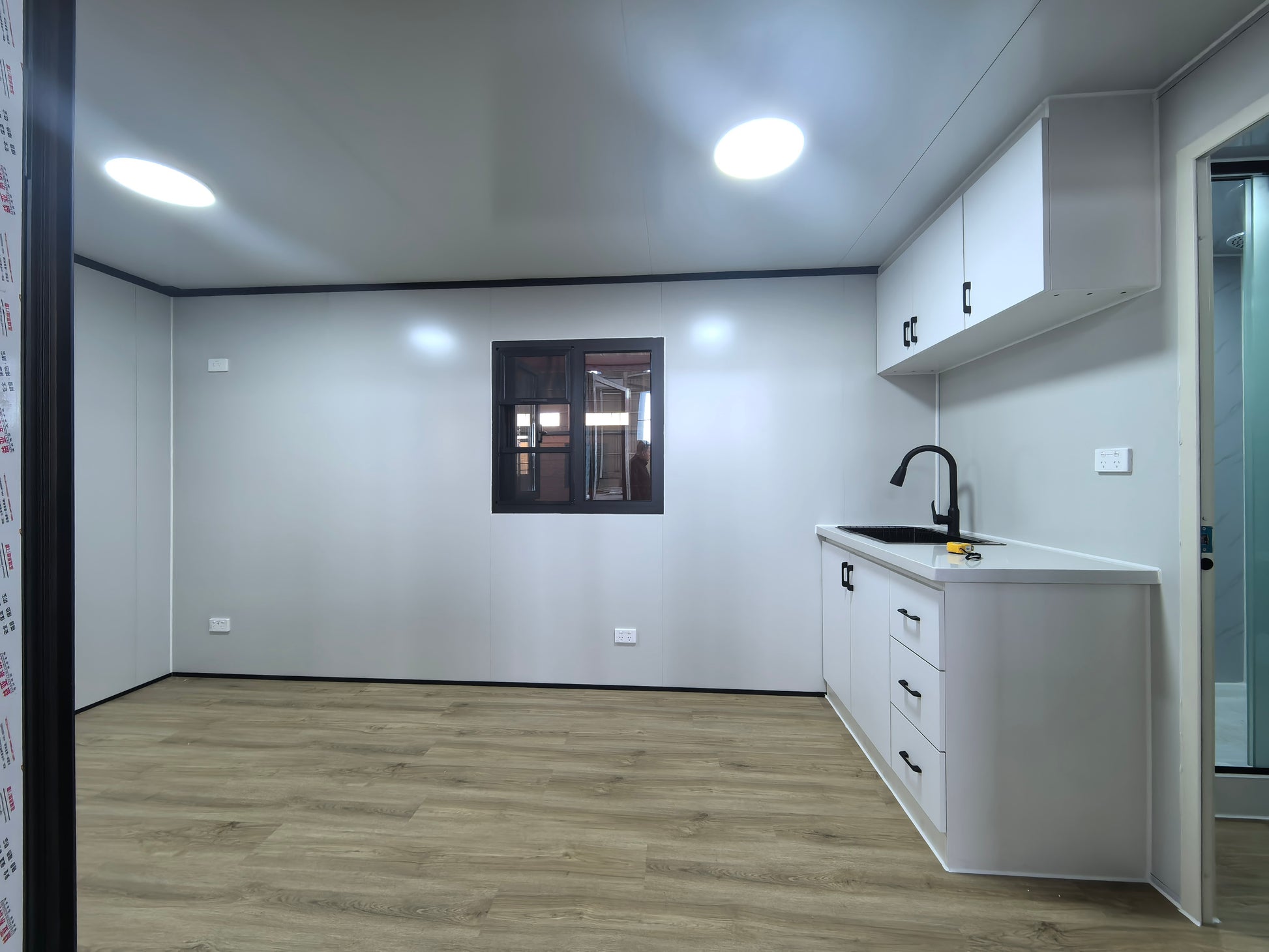 Modern kitchen with white cabinets and a window on a white wall.
