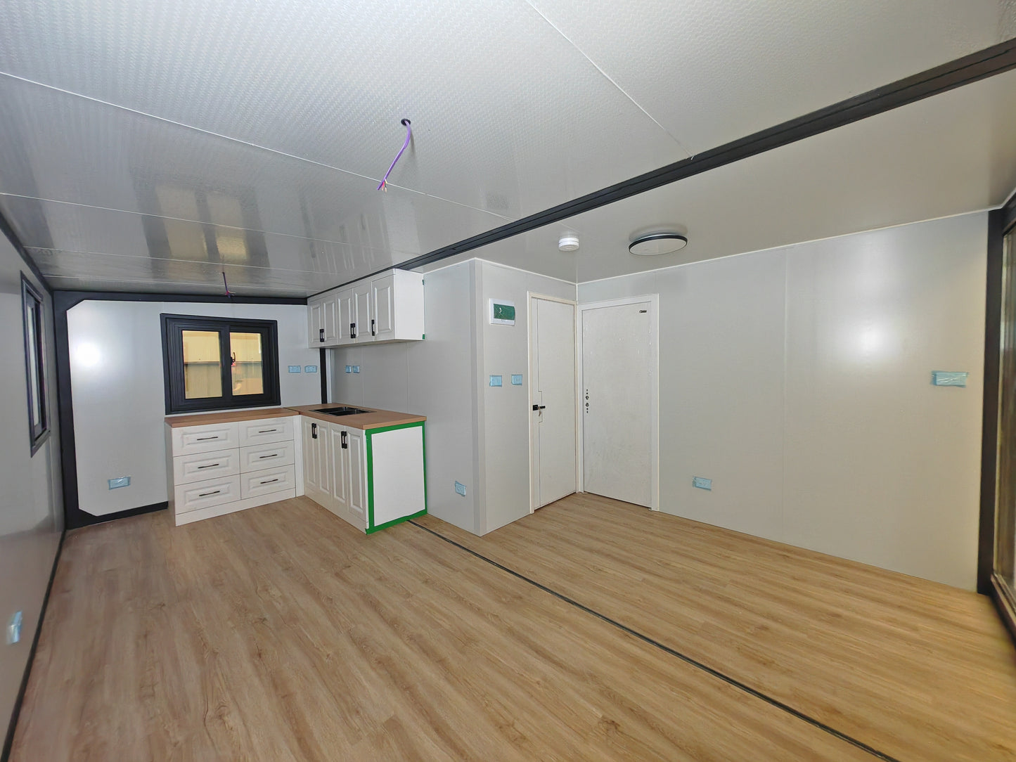 Modern kitchen with white cabinets and wooden flooring in a compact living space.