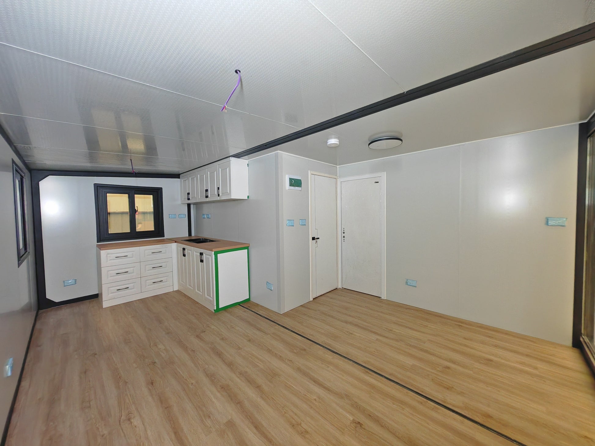 Modern kitchen with white cabinets and wooden flooring in a compact living space.