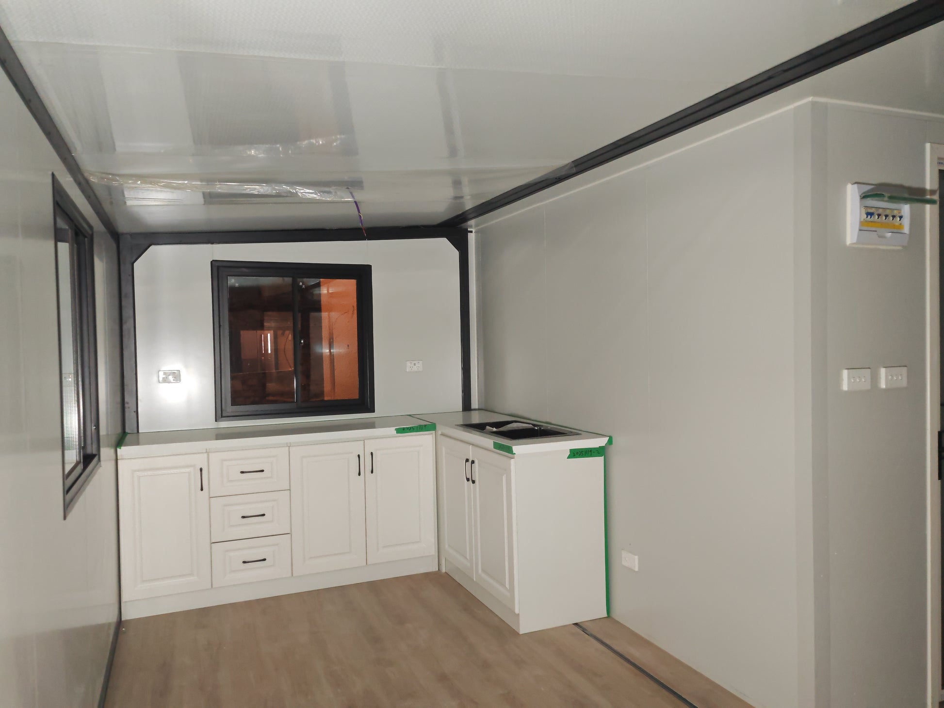 Small kitchenette with white cabinets, countertop, and window.