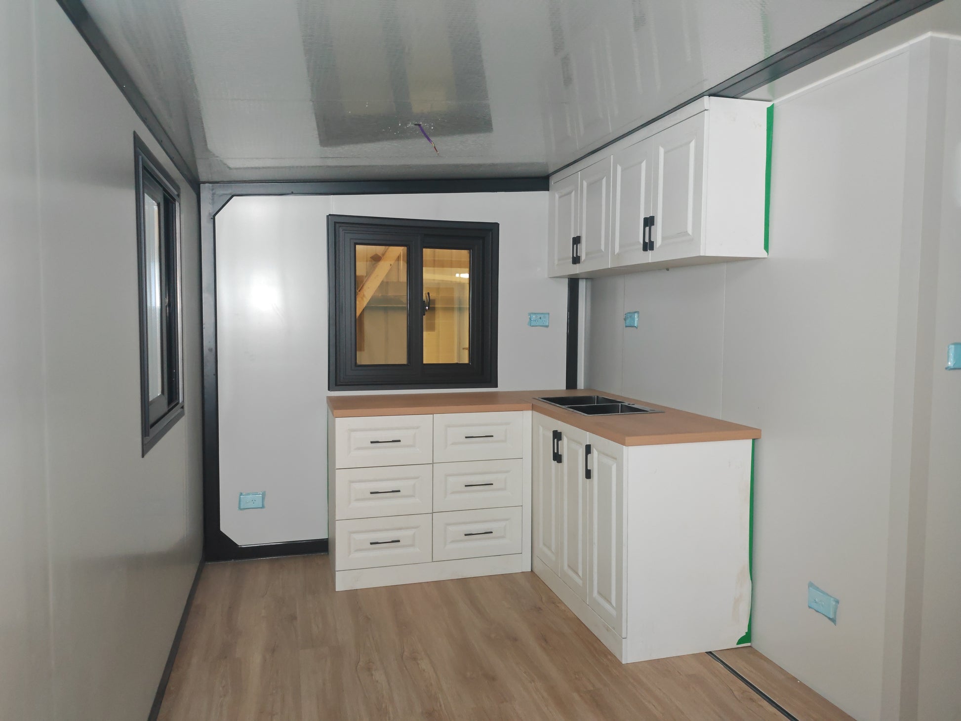 A  kitchen with white cabinets and wooden countertop