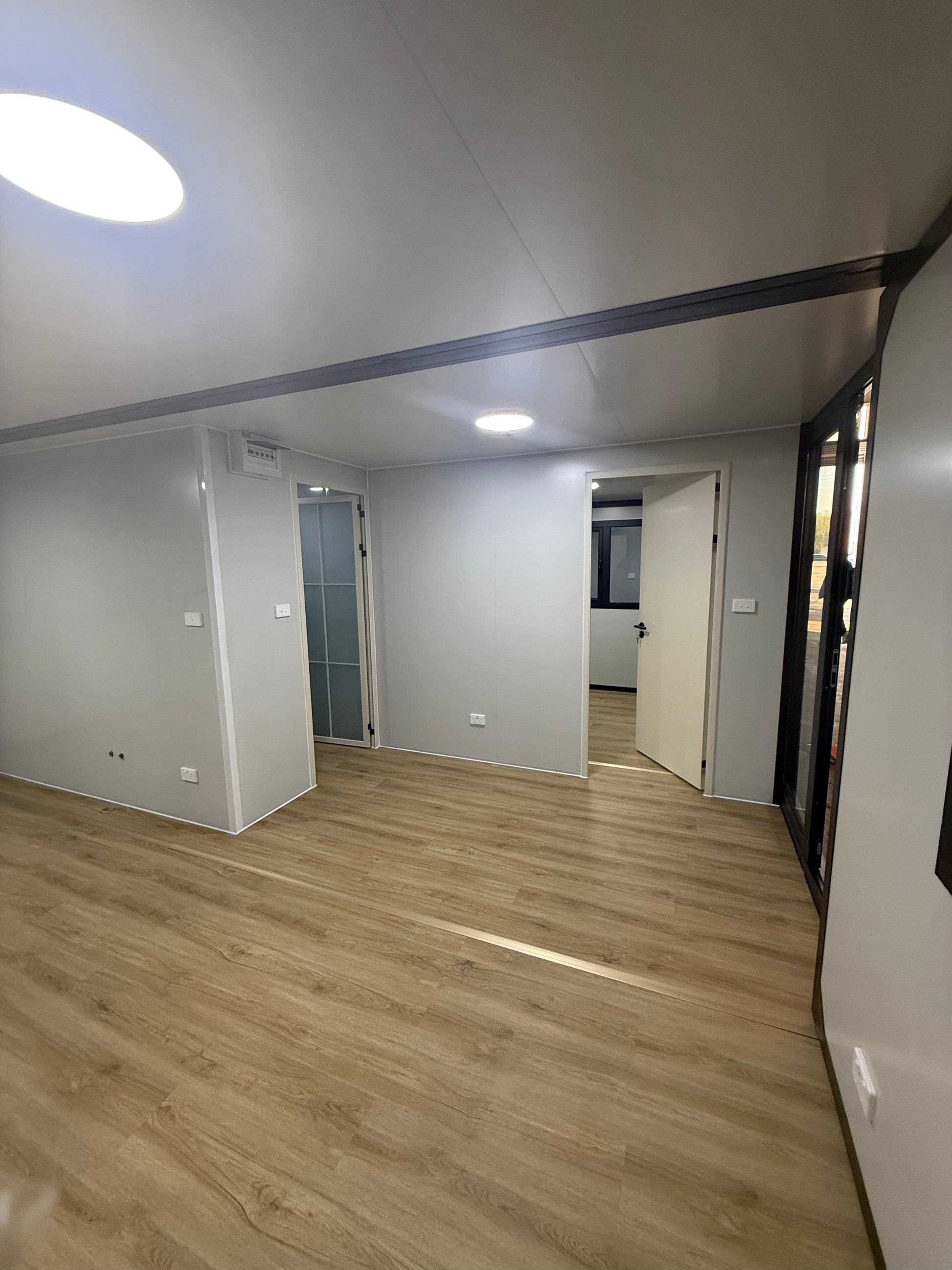 Compact living space with a bed raised from the floor, wooden wall, and white walls.