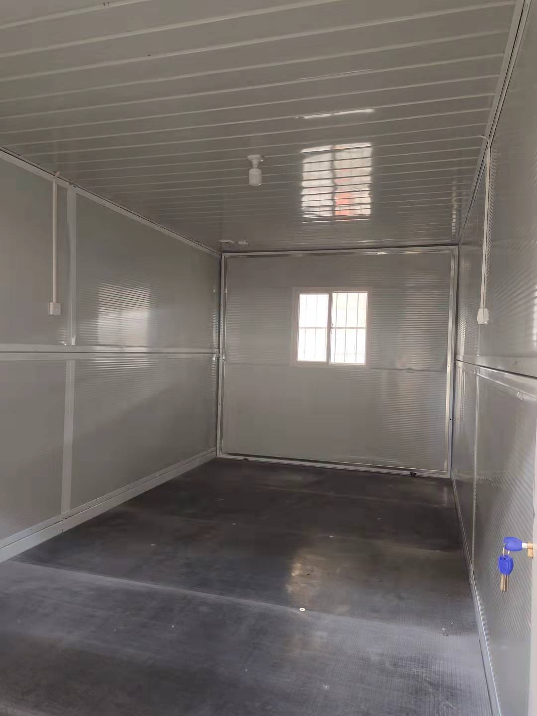 Gray interior of a mobile trailer with a window and door.