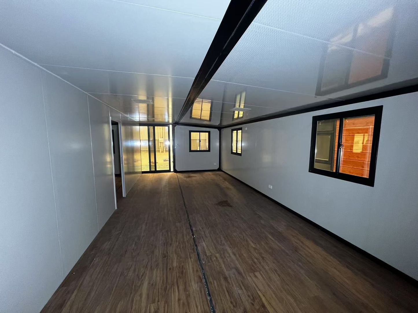 A room with wooden floor and large windows  and a door