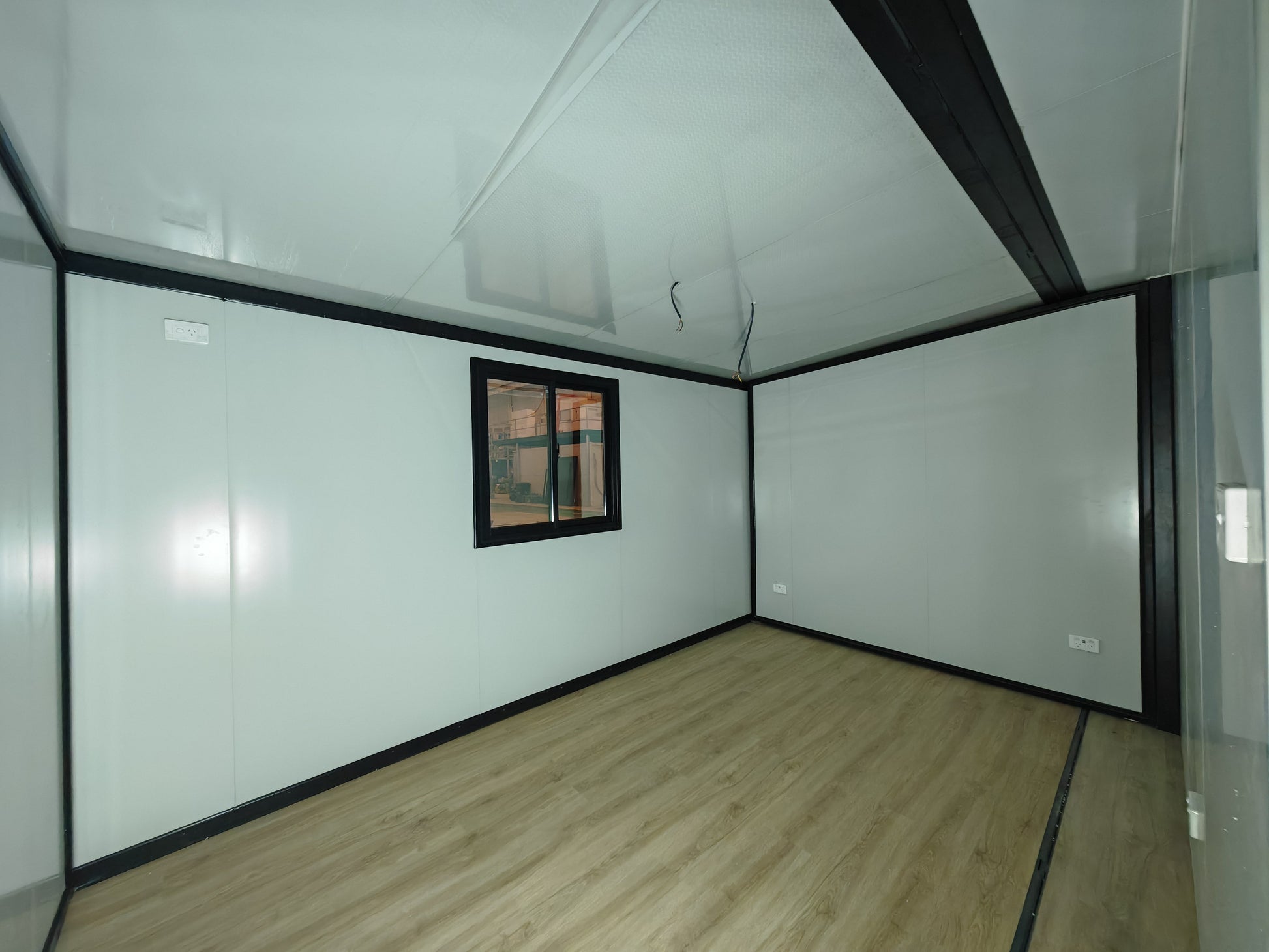 Empty room with white walls, wooden floor, and a small window.
