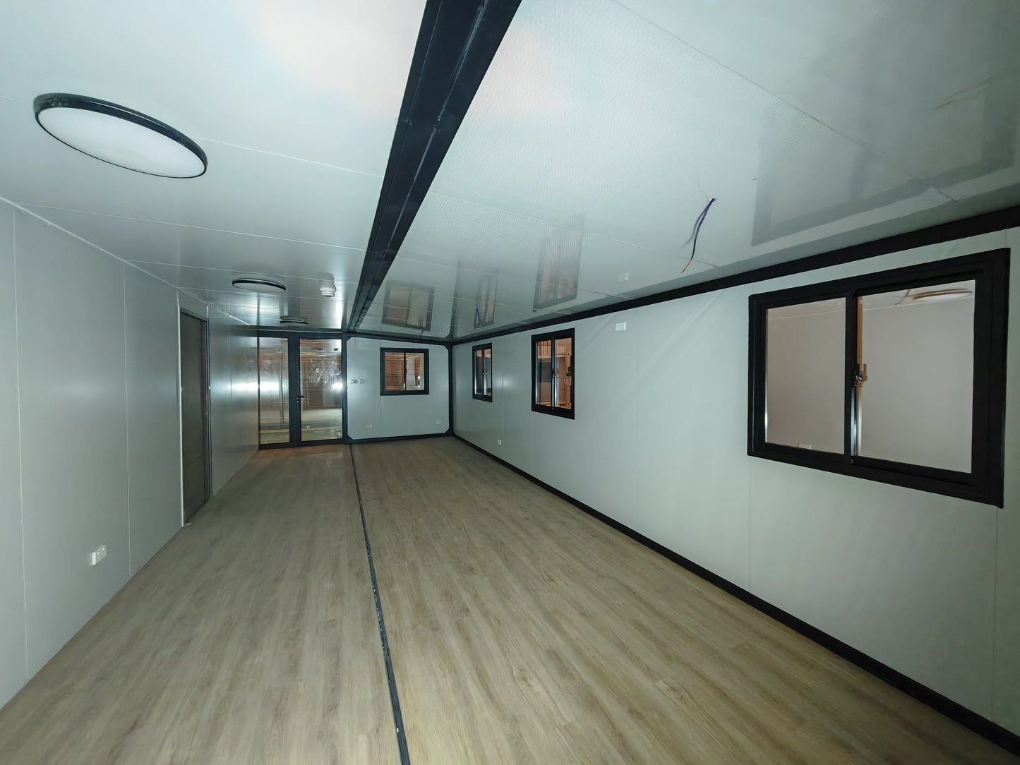Long, narrow room with white walls and wooden floor