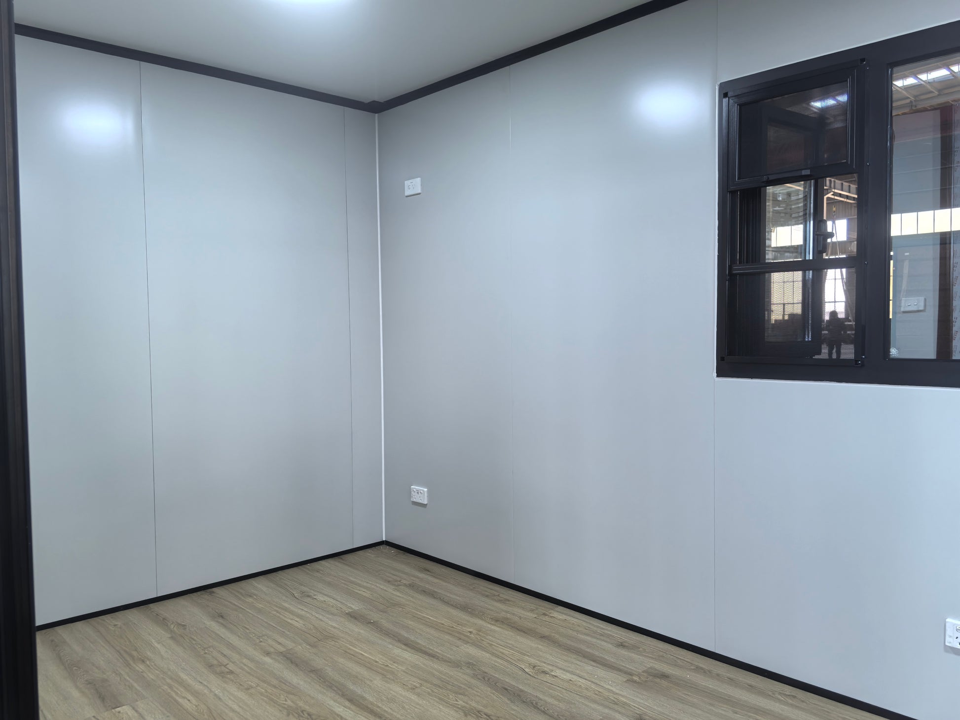Empty room with white walls, a window, and wooden flooring.
