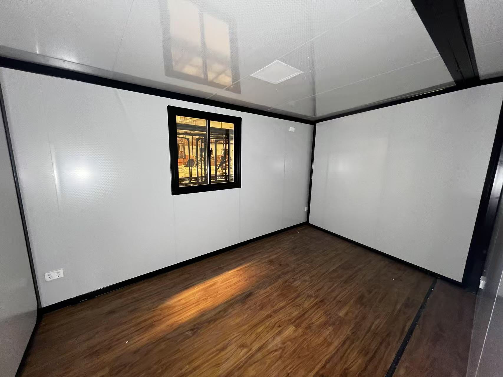 Small room with white walls, wooden floor, and a small window.