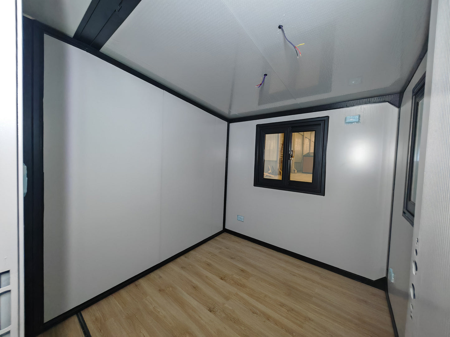 Small room with white walls, wooden floor, and a window.