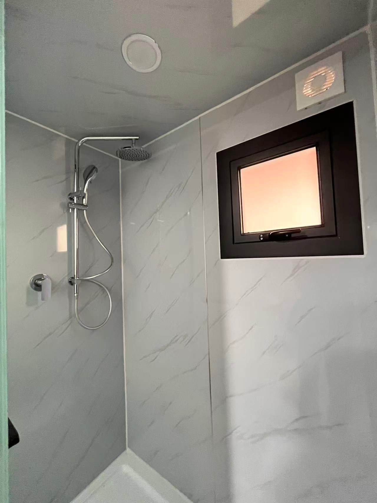 Modern shower setup with a small window in a tiled bathroom.