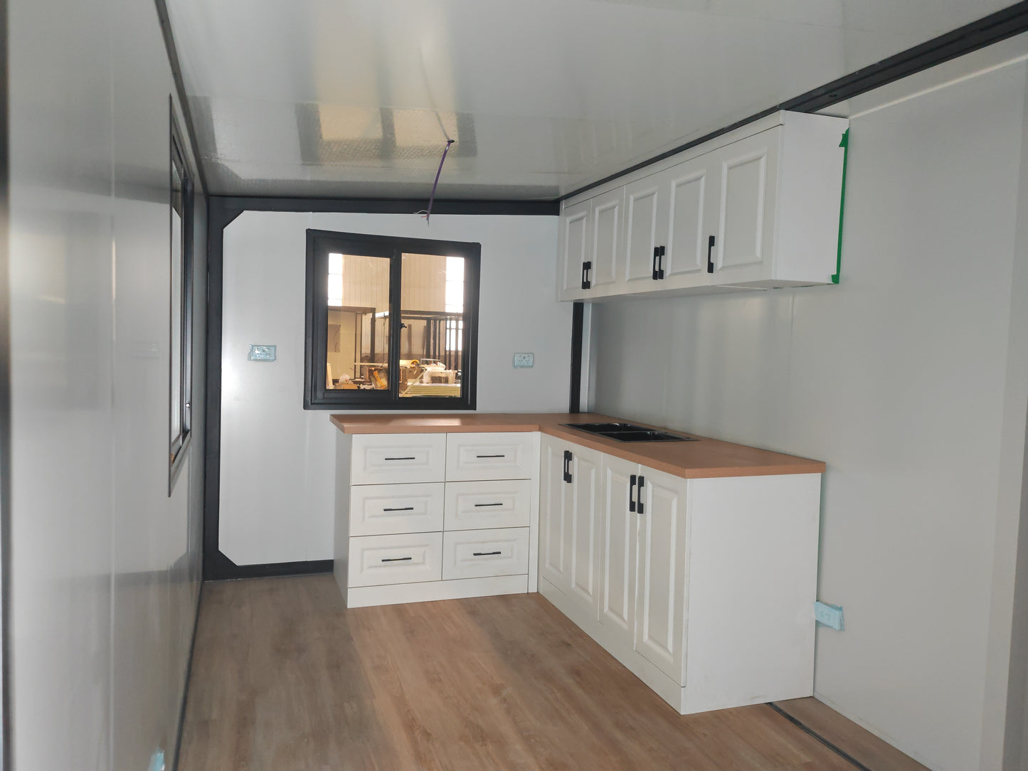 Modern kitchen with white cabinets, wooden countertops, and a window view.