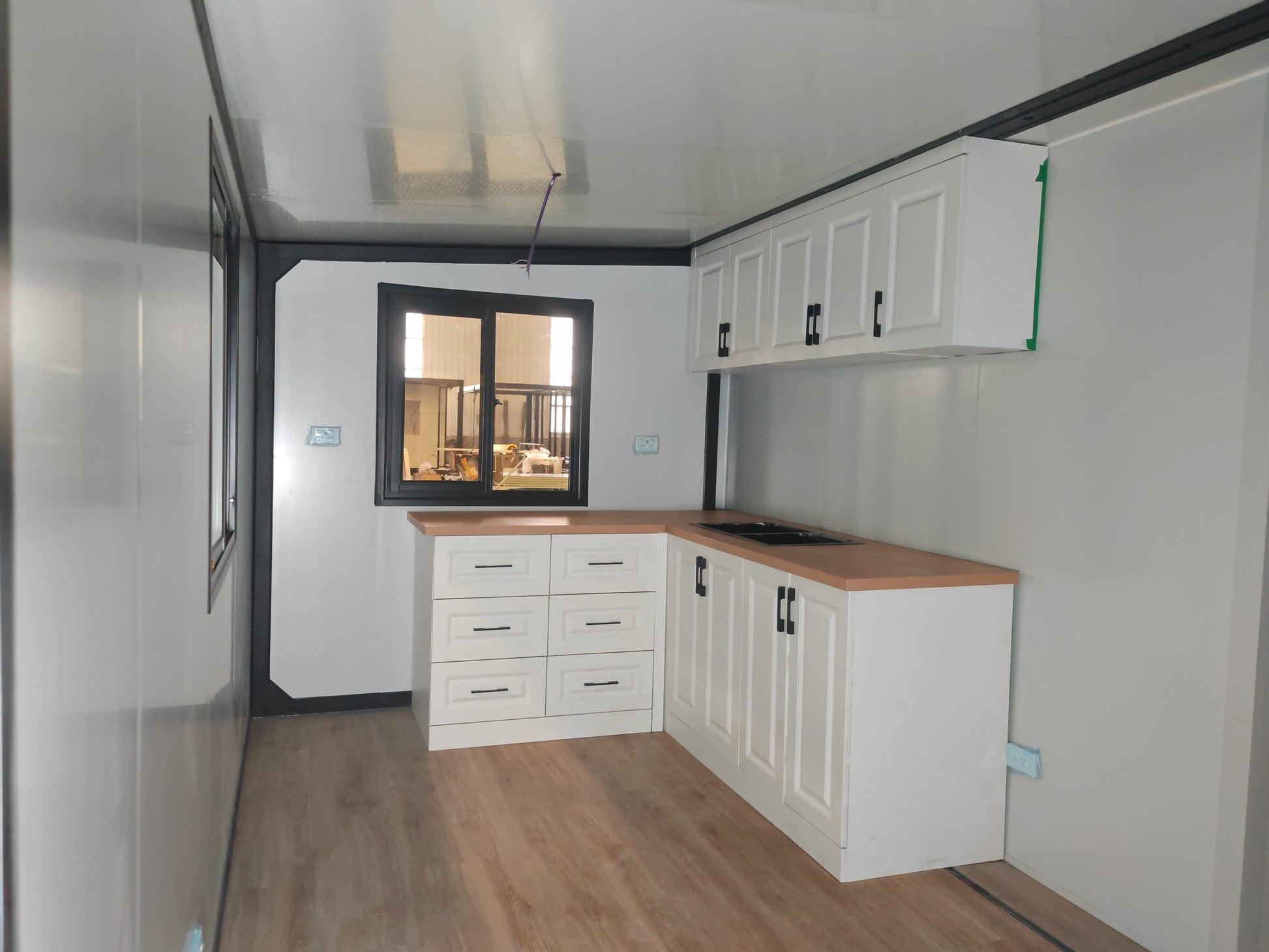 Modern kitchen with white cabinets, wooden countertops, and a window view.