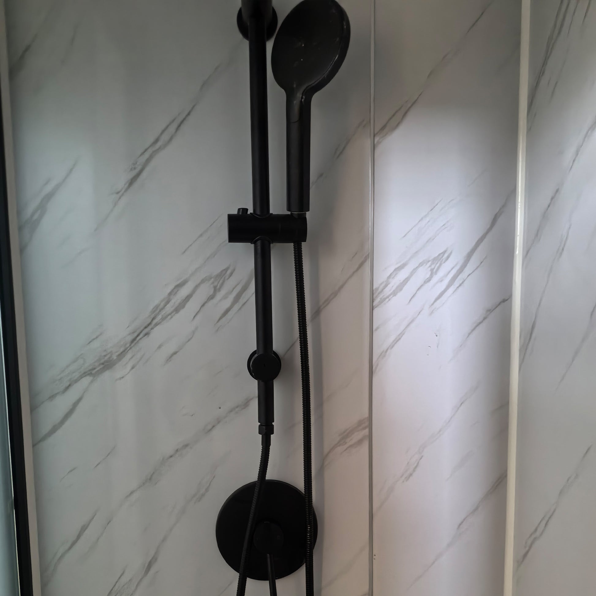 Black shower head and hose against a marble-patterned wall, watermark certified