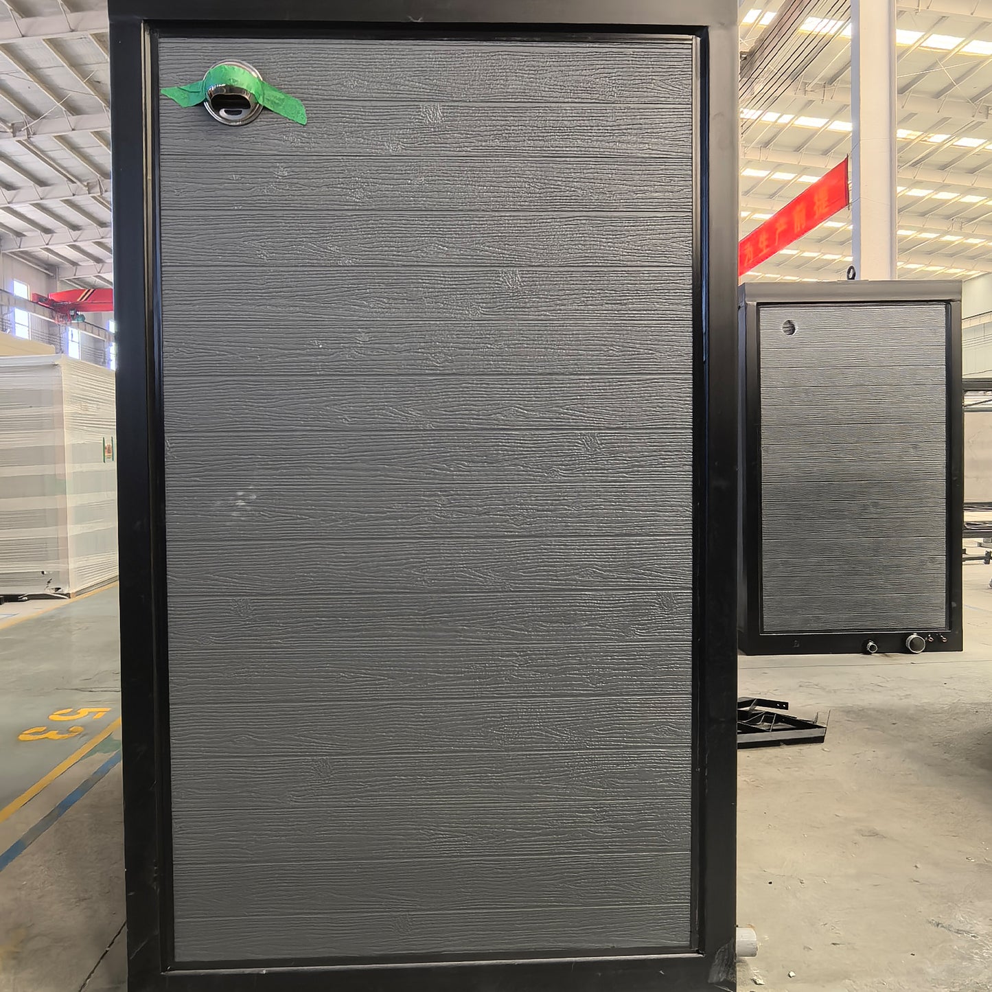 Large gray panel with a green logo on a factory floor, bathroom side view