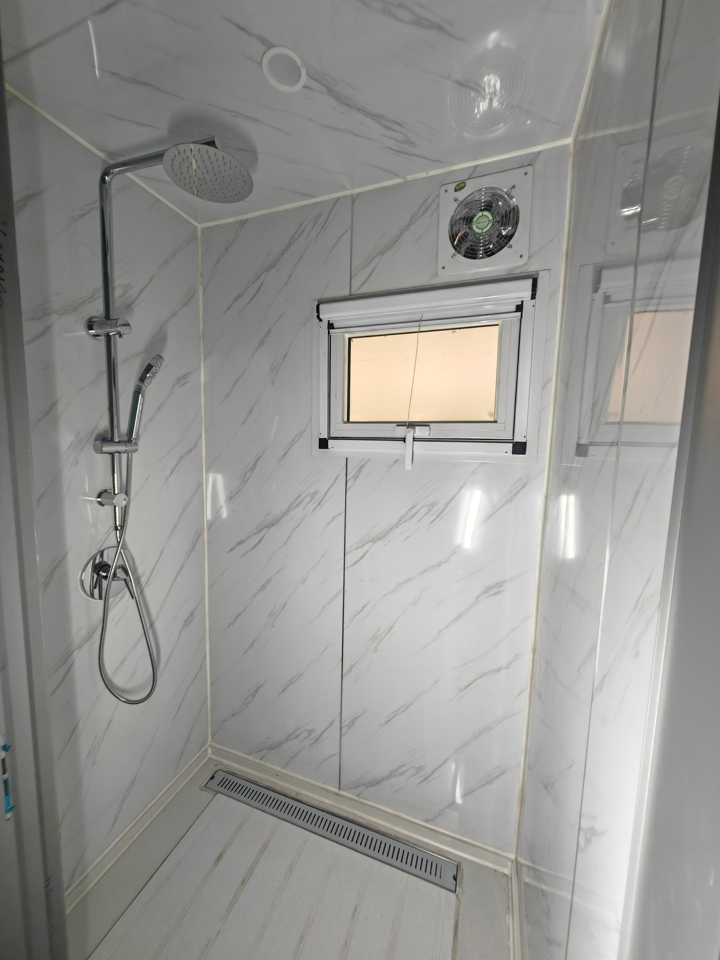 Shower enclosure with tiled like walls and a small window.